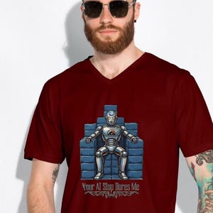 Op de afbeelding: Bordeauxrode V-hals T-shirt met een robotillustratie zittend op een blauwe troon. De robot is zilverkleurig met een zwart-oranje embleem. De tekst "Your AI Slop Bores Me" staat eronder.