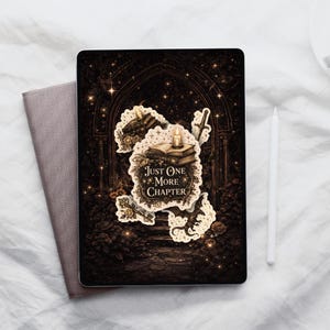 May include: A black tablet case with a sticker featuring the text "Just One More Chapter" and illustrations of books, a sword, and a key. A gray book and a white stylus are next to the tablet.