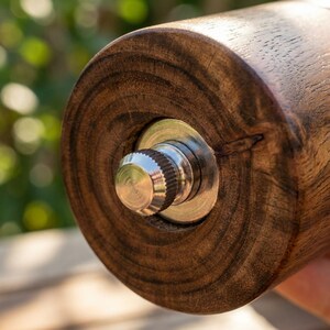 Close up of acacia wood salt grinder engraved S letter detail, warm natural wood grain texture, premium kitchen accessory