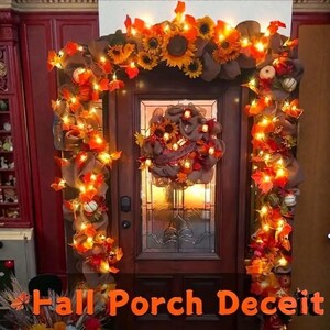 Può includere: Una porta decorata a tema autunnale. La porta è incorniciata da una ghirlanda di girasoli, foglie autunnali e luci. Una ghirlanda con girasoli e decorazioni autunnali è appesa alla porta. Il testo "Fall Porch Deceit" è in basso.