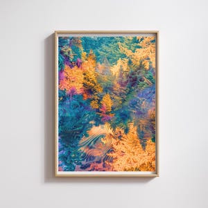 May include: A framed art print featuring a vibrant, abstract landscape. The artwork showcases a colorful forest with shades of orange, teal, and purple. The image is framed in a light wood frame, adding a natural touch to the artwork.