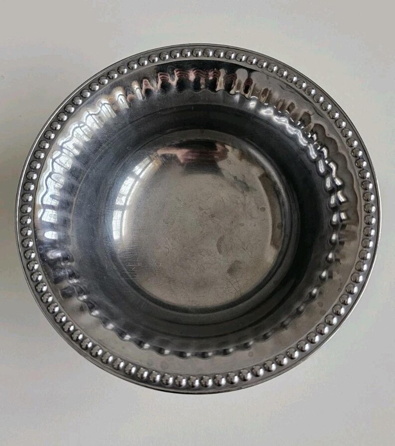 Puede incluir: Un cuenco redondo de acero inoxidable con borde de cuentas. El borde presenta un dise&ntilde;o festoneado y el interior es liso y reflectante. Este cuenco es adecuado para servir o decorar.