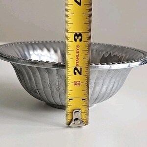 Puede incluir: Un peque&ntilde;o cuenco plateado con un borde con cuentas y un exterior acanalado. El cuenco mide aproximadamente 7,6 cm de alto, medido con una cinta m&eacute;trica amarilla. El cuenco tiene un dise&ntilde;o simple y elegante.