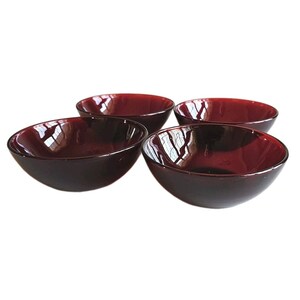 May include: Four dark red glass bowls. Each bowl has a rounded shape with a smooth, glossy finish. The bowls are arranged in a group, showcasing their similar design and color. The bowls are suitable for serving food.