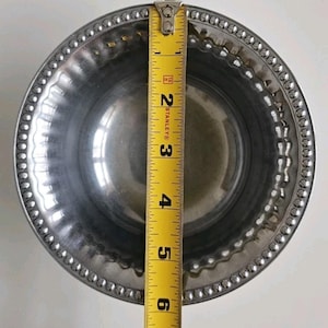 Puede incluir: Un cuenco de metal plateado brillante con un borde con cuentas. Una cinta m&eacute;trica amarilla Stanley se coloca sobre el cuenco, mostrando un di&aacute;metro de aproximadamente 15 cm.