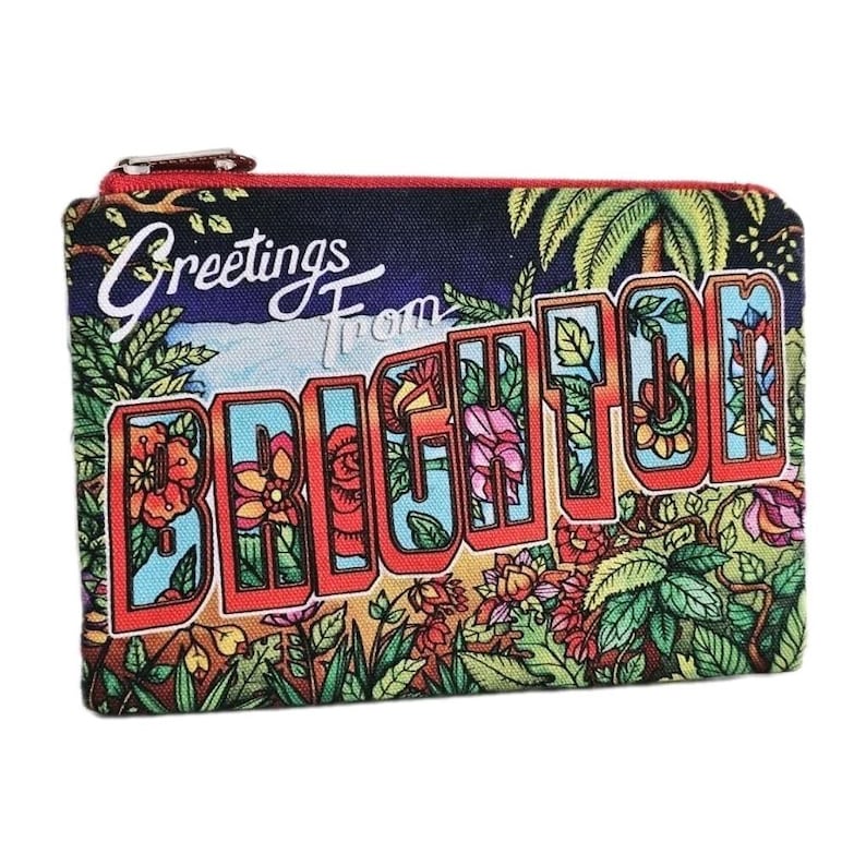 Pu&ograve; includere: Un portamonete rettangolare con chiusura a zip. Il design presenta le parole "Greetings From BRIGHTON" in stile cartolina vintage. Lo sfondo &egrave; blu scuro con illustrazioni floreali e di palme.