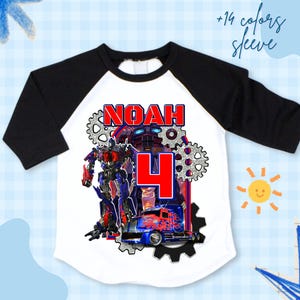 Könnte beinhalten: Weißes und schwarzes Raglan-Ärmel-Shirt mit einem Transformers-Motiv. Das Shirt zeigt den Namen "NOAH" und die Zahl "4" in Rot. Der Text "+14 Farben Ärmel" ist ebenfalls sichtbar.