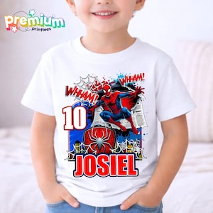 Pu&ograve; includere: T-shirt bianca con grafica colorata di Spider-Man, la scritta "WHAM!" e il numero "10". Il nome "JOSIEL" &egrave; stampato in rosso. La maglietta ha il logo "Premium Printtees".