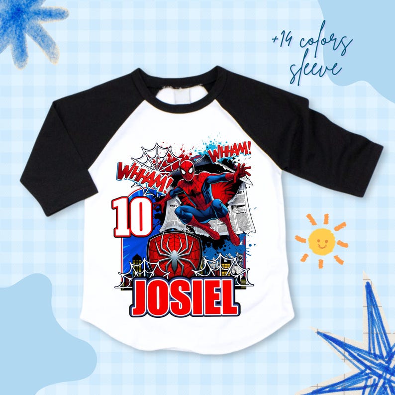 Pu&ograve; includere: T-shirt bianca e nera con maniche a raglan con grafica di Spider-Man. La grafica include il numero 10, il nome "JOSIEL" e la parola "WHAM!". La maglietta ha uno sfondo blu e bianco con un disegno di sole e stella.