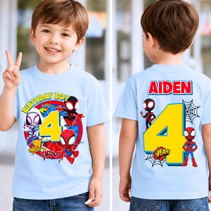 May include: Light blue birthday t-shirt featuring Spider-Man characters. The front displays a large yellow number 4, surrounded by comic book graphics and the words "BIRTHDAY BOY." The back has the name "AIDEN" and a yellow number 4.