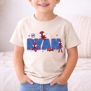 Może przedstawiać: Biały ceramiczny kubek z czarnym uchwytem i napisem "But First, Coffee" pogrubioną czcionką. Kubek jest umieszczony na rozmytym tle, sugerującym przytulne otoczenie.