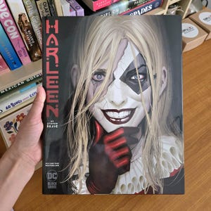Puede incluir: Cómic "Harleen" de Stjepan Sejic. La portada muestra un primer plano de una mujer rubia con maquillaje de arlequín y una sonrisa siniestra. El logo de DC Black Label es visible. Es un bestseller.