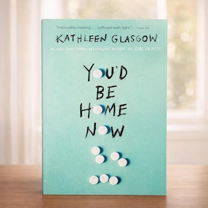 Puede incluir: Una portada de libro con fondo turquesa presenta el título "You'd Be Home Now" con gráficos blancos en forma de pastillas. El nombre de la autora, Kathleen Glasgow, está encima del título. La portada también incluye una cita de Vanity Fair.