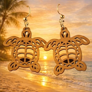 May include: A pair of wooden turtle earrings with gold-colored hooks. The earrings are intricately cut with a detailed design. The background shows a beach scene with a sunset, palm trees, and ocean waves.