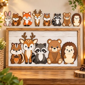 May include: A rectangular wooden wall sign featuring five layered wooden animal cutouts: a chipmunk holding an acorn, a deer, a raccoon, a bear, and a hedgehog. The sign has a light-colored horizontal plank background and a dark brown wooden frame.