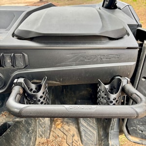 Könnte beinhalten: Schwarzer ATV-Innenraum mit dem Text "ZFORCE" und zwei Getränkehaltern. Das ATV hat ein strukturiertes Armaturenbrett und einen schwarzen Griff mit dem Text "CFMOTO".