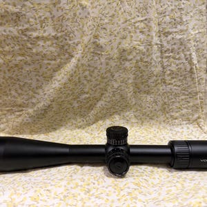 Op de afbeelding: Een witte keramische mok met een zwart oor en de tekst "But First, Coffee" in een vetgedrukte, zwarte letter. De mok staat tegen een vage achtergrond, wat een gezellige setting suggereert.