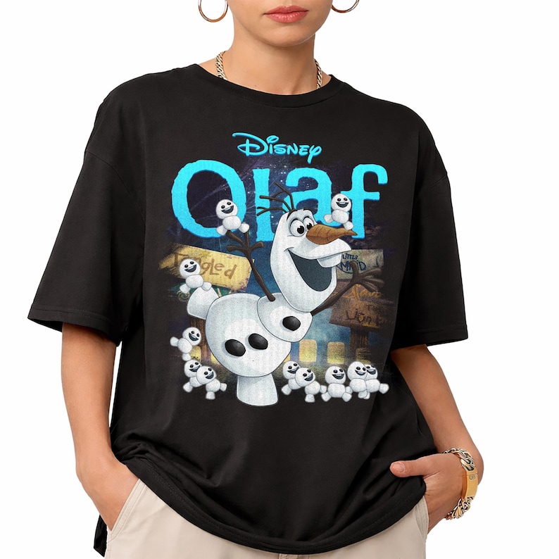 May include: A black short-sleeve t-shirt featuring a graphic print of the character Olaf from Disney. The design includes the text Disney Olaf in bright blue, surrounded by multiple small snowgie figures against a dark, textured background.