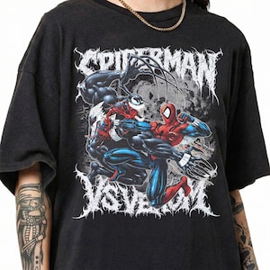 May include: Black t-shirt with a graphic of Spider-Man fighting Venom. The design includes the words "SPIDERMAN" and "VS VENOM" in a stylized font. The artwork shows the characters in action, with bright colours.