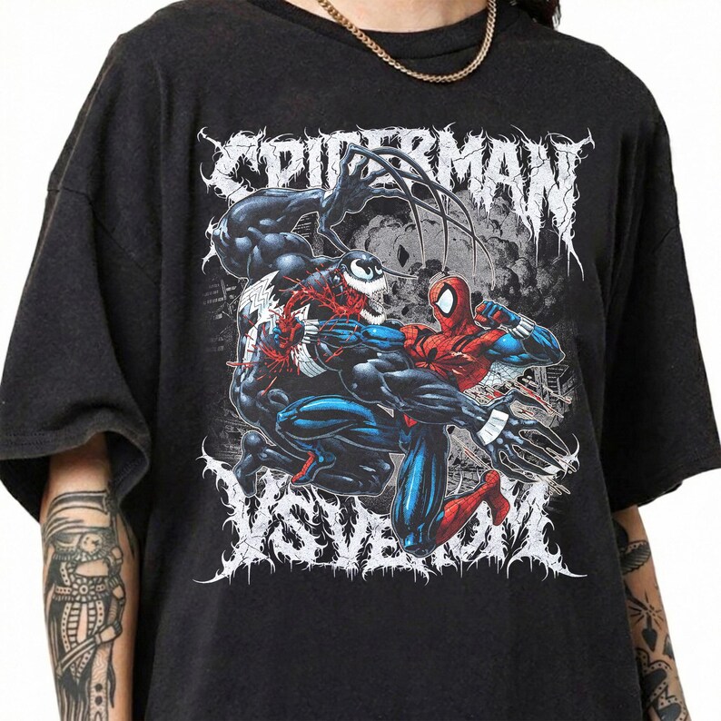 May include: Black t-shirt with a graphic of Spider-Man fighting Venom. The design includes the words "SPIDERMAN" and "VS VENOM" in a stylized font. The artwork shows the characters in action, with bright colours.