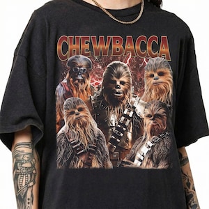 May include: Dark grey t-shirt with a graphic of Chewbacca from Star Wars. The design features multiple images of Chewbacca with the word "Chewbacca" in a gold and red font. The t-shirt has short sleeves.