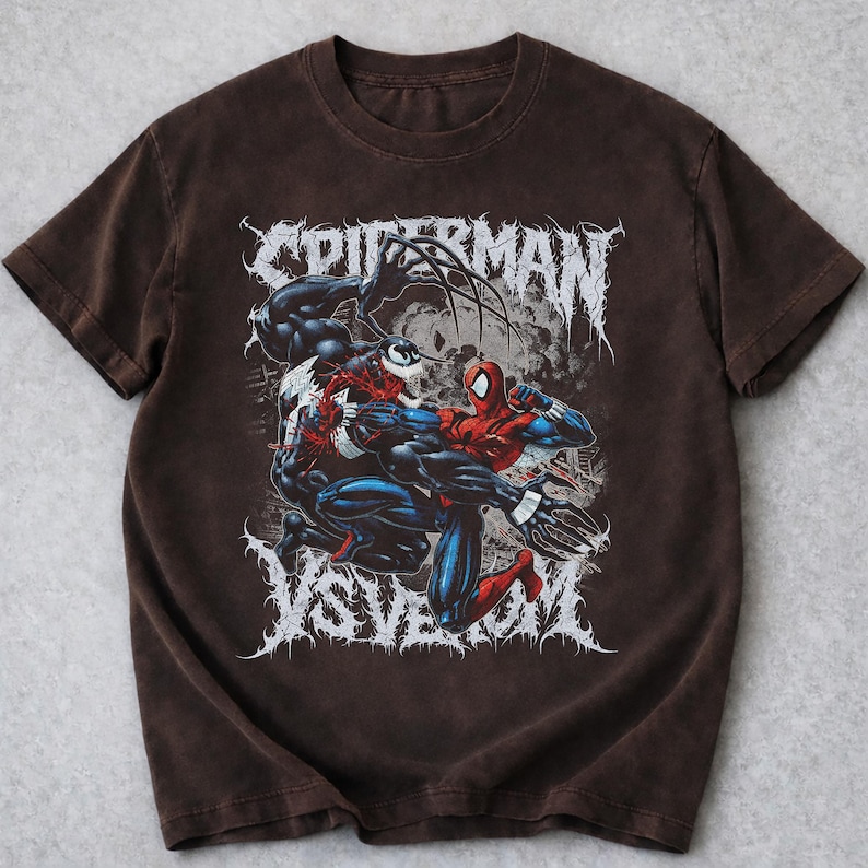 May include: A brown t-shirt with a graphic of Spider-Man fighting Venom. The design includes the words "SPIDERMAN" and "VS VENOM" in a stylized font. The image shows the two characters in a dynamic pose.