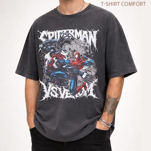 May include: Charcoal grey t-shirt with a graphic of Spider-Man fighting Venom. The design includes the words "SPIDERMAN" and "VS VENOM" in a stylized font. The shirt is labelled "PEPPER T-SHIRT COMFORT" in the upper right corner.