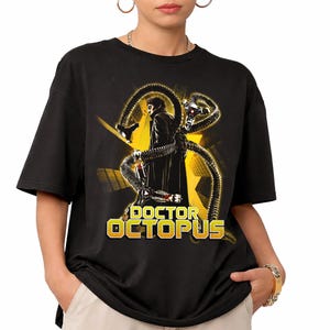 May include: A black short-sleeve t-shirt featuring a graphic print of Doctor Octopus with mechanical tentacles. The design includes a yellow star background and the text DOCTOR OCTOPUS in bold yellow lettering at the bottom of the graphic.