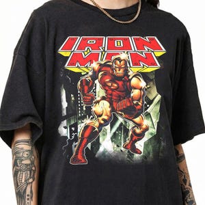 May include: A white ceramic mug with a black handle and the text "But First, Coffee" in a black, bold font. The mug is on a wooden surface. The mug is approximately 10 cm tall.