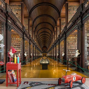 May include: A red toy race car with the number 1 on the side sits on a gray rug with a race track design. A red side table with books and a lamp is in front of a library backdrop with bookshelves and busts.