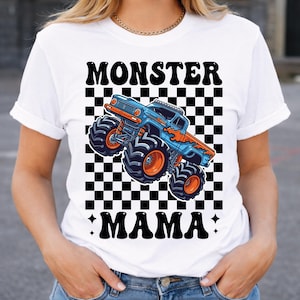 May include: White t-shirt featuring a blue and orange monster truck graphic on a black and white checkered background. The words "MONSTER" and "MAMA" are printed above and below the truck design in black.