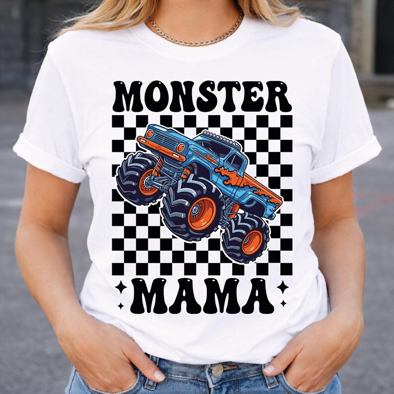 May include: White t-shirt featuring a blue and orange monster truck graphic on a black and white checkered background. The words "MONSTER" and "MAMA" are printed above and below the truck design in black.