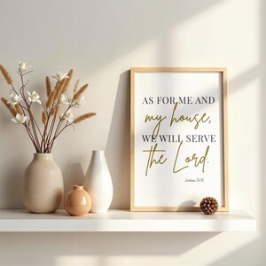 May include: A framed print with the text "AS FOR ME AND my house, WE WILL SERVE the Lord." in black and gold lettering. The print is on a white background. Beside it are vases with flowers.