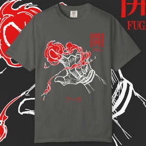 May include: A gray t-shirt featuring a red and white graphic of a hand holding a stylized red flower. The Japanese characters and the word "FUGA" are printed in red. The shirt has a crew neck and short sleeves.