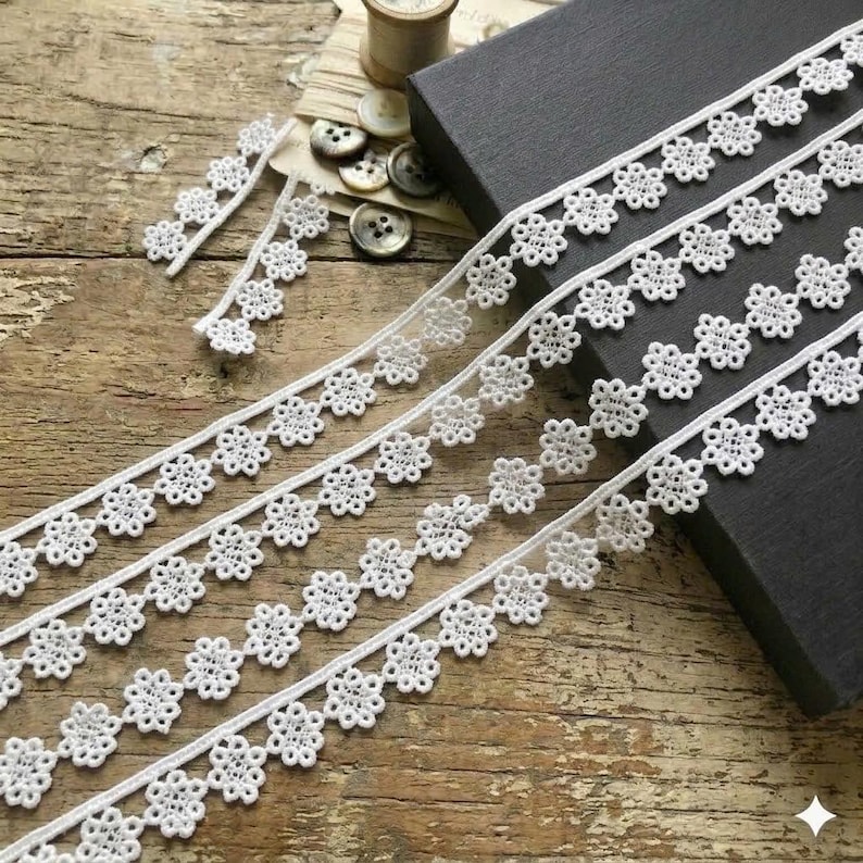 May include: A white ceramic mug with a black handle and the text "But First, Coffee" in a black, handwritten-style font. The mug is on a white surface.