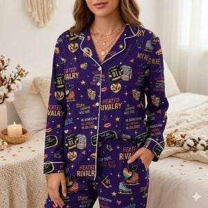 May include: Purple pajama set with a white trim, featuring a pattern of ice skates, hockey jerseys, and text. The text includes phrases like "Heated Rivalry" and "What Happens SafT to Your Heart".