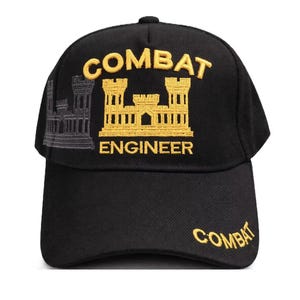 May include: Black baseball cap with the word "COMBAT" embroidered in gold on the front and the word "ENGINEER" below a gold castle emblem. The word "COMBAT" is also embroidered on the side of the cap.