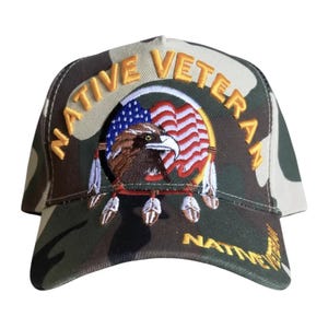 May include: Camouflage baseball cap with the words "NATIVE VETERAN" embroidered in gold. The cap features an eagle, American flag, and feathers. A stylish accessory for veterans.