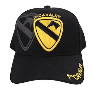 May include: Black baseball cap featuring the "1st Cavalry" emblem. The cap has a curved brim and a structured crown. The emblem is a yellow shield with a black diagonal stripe and a horse head, embroidered in gold thread.