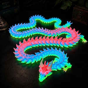May include: A long, articulated dragon figurine featuring a vibrant gradient of neon blue, green, and pink colors. The creature has a segmented body with sharp, spiky scales along its back and a detailed head with two small, light-colored horns.
