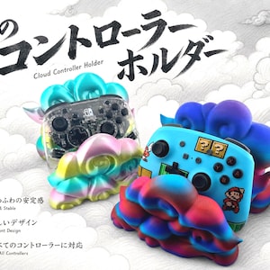 May include: Two cloud-shaped controller holders with a gradient finish. One holder is iridescent blue, green, and yellow, supporting a transparent black game controller. The other is blue, purple, and red, holding a blue controller with Mario graphics.
