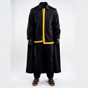 Puede incluir: Uniforme negro con ribetes amarillos, que incluye chaqueta, pantalón y capa. La chaqueta tiene cremallera y ribetes amarillos. El atuendo se completa con guantes y botas negras. El uniforme se muestra sobre un fondo blanco.