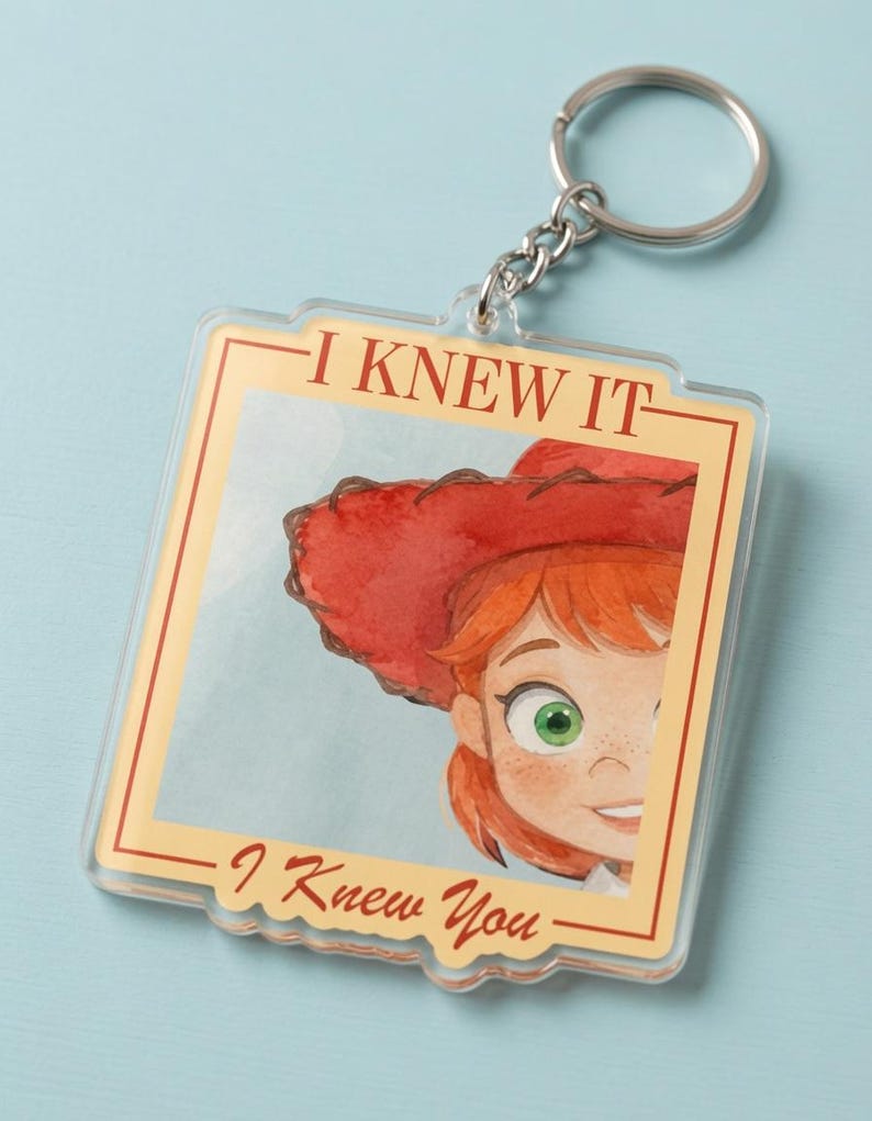 May include: A square acrylic keychain featuring a watercolor illustration of a person with red hair and a red cowboy hat. The text "I KNEW IT" is printed at the top and "I Knew You" at the bottom in a red serif font within a cream border.