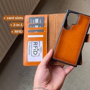 May include: A tan leather wallet phone case featuring a detachable magnetic phone shell, multiple card slots, and a clear ID window. The interior includes text labels for card slots, 2-in-1, and RFID protection. The case has a smooth finish.