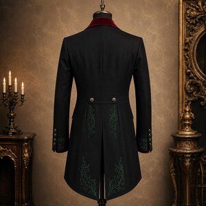 May include: Black tailcoat with a burgundy velvet collar and cuffs. The back of the coat features decorative green embroidery and ornate buttons. The coat is displayed on a mannequin.
