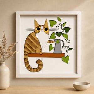 May include: A framed art piece featuring a stylized cat with brown and tan stripes, sitting on a brown shelf. Green heart-shaped leaves and a gray pitcher are also depicted. The artwork is set against a white background.