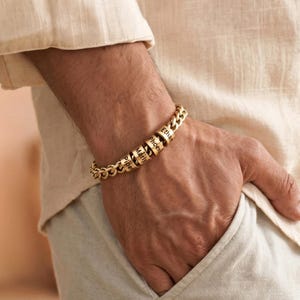 May include: A gold-toned chain link bracelet featuring three cylindrical beads, each engraved with a name. The beads are inscribed with the names Piper, Marly, and Phoenix, and the bracelet is secured with a matching gold-toned metal clasp.
