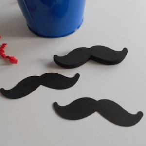 May include: Three black paper mustache cutouts on a white surface.