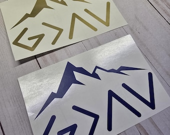 May include: Two stickers with a mountain range design and the text "G > AV". One sticker is gold, the other is navy blue. The stickers are on a white background.