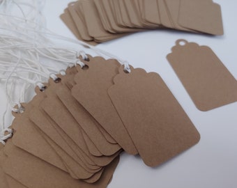 May include: A stack of brown paper gift tags with white string attached. The tags are rectangular with rounded corners and have a hole punched at the top.